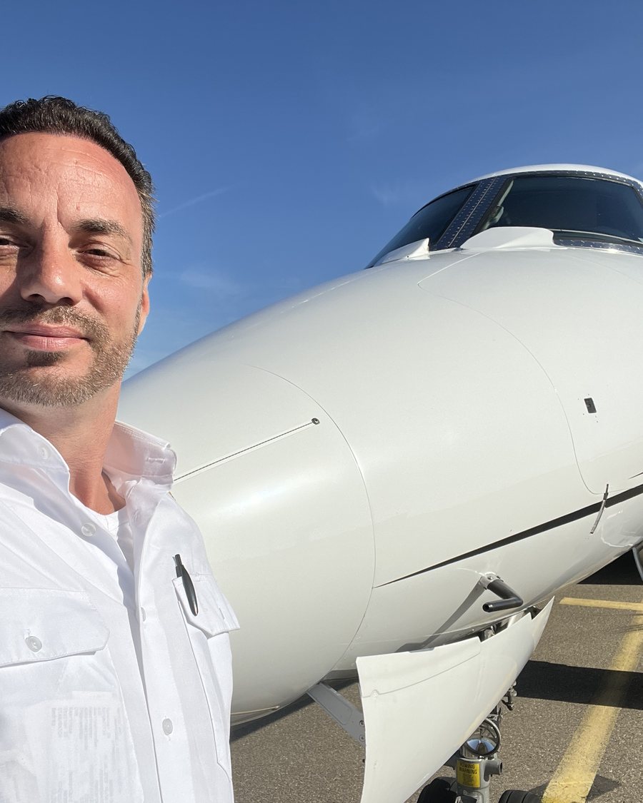 Fabian Voncken, pilote de ligne, en chemise d'uniforme devant un Falcon 2000LX